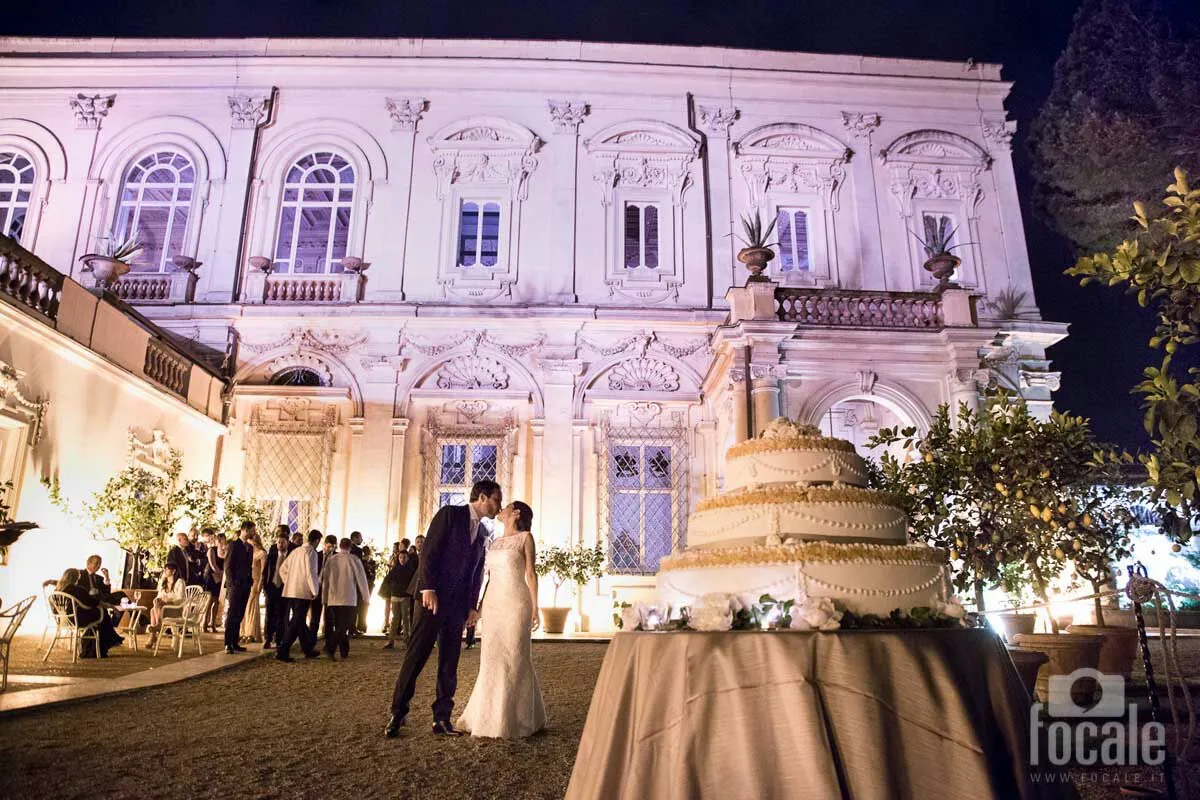 Sposi davanti alla facciata illuminata di una villa storica la sera