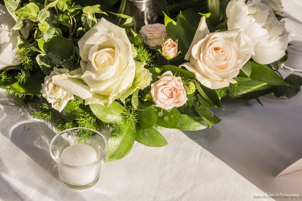 Composizione di rose bianche e rosa su una tavola apparecchiata