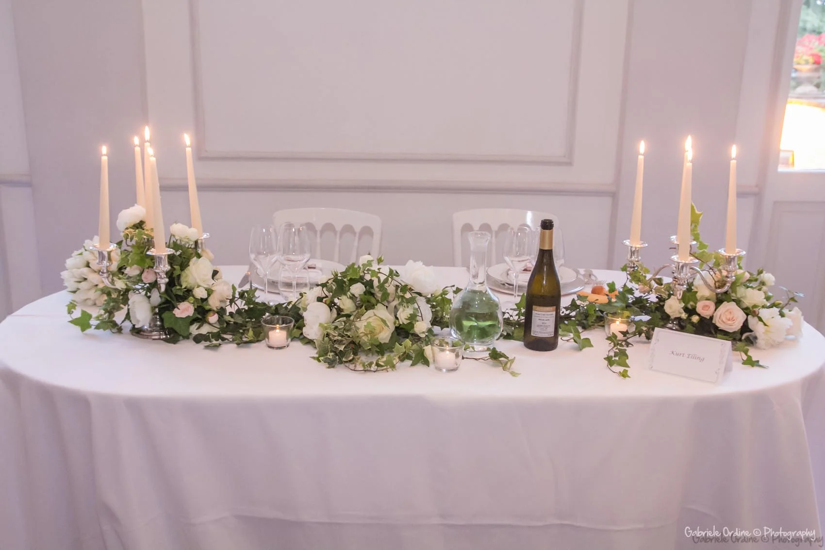 Tavolo degli sposi con candele e composizione floreale bianca