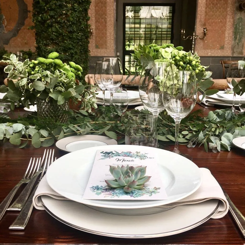 Mise en place con piatto bianco, segnaposto e centrotavola verde