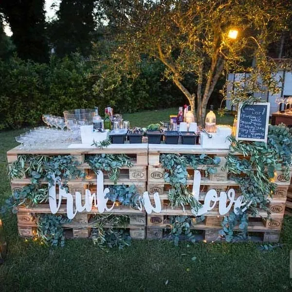 Angolo rustico in giardino con pallet in legno, fiori e lanterne