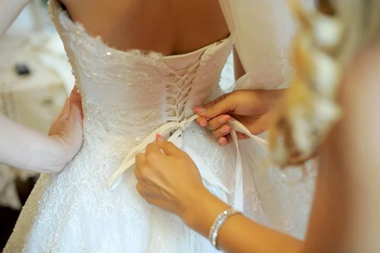 Sposa che allaccia il corsetto dell’abito