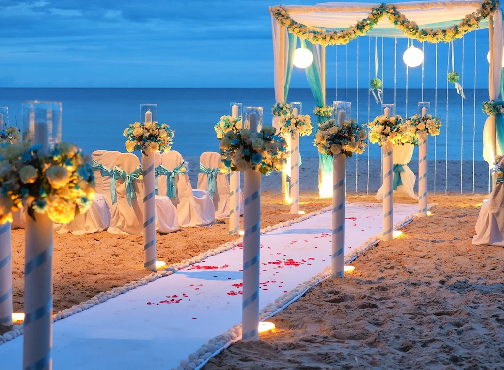 Cerimonia sulla spiaggia al tramonto con archi fioriti