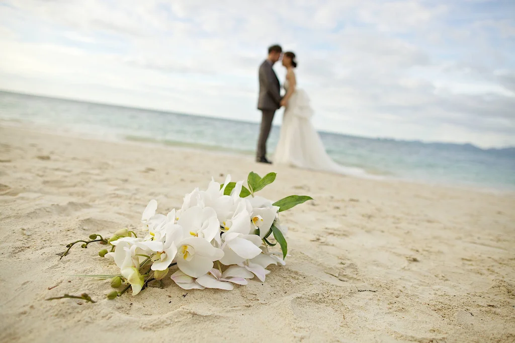 Sposi sulla spiaggia con fiori in primo piano