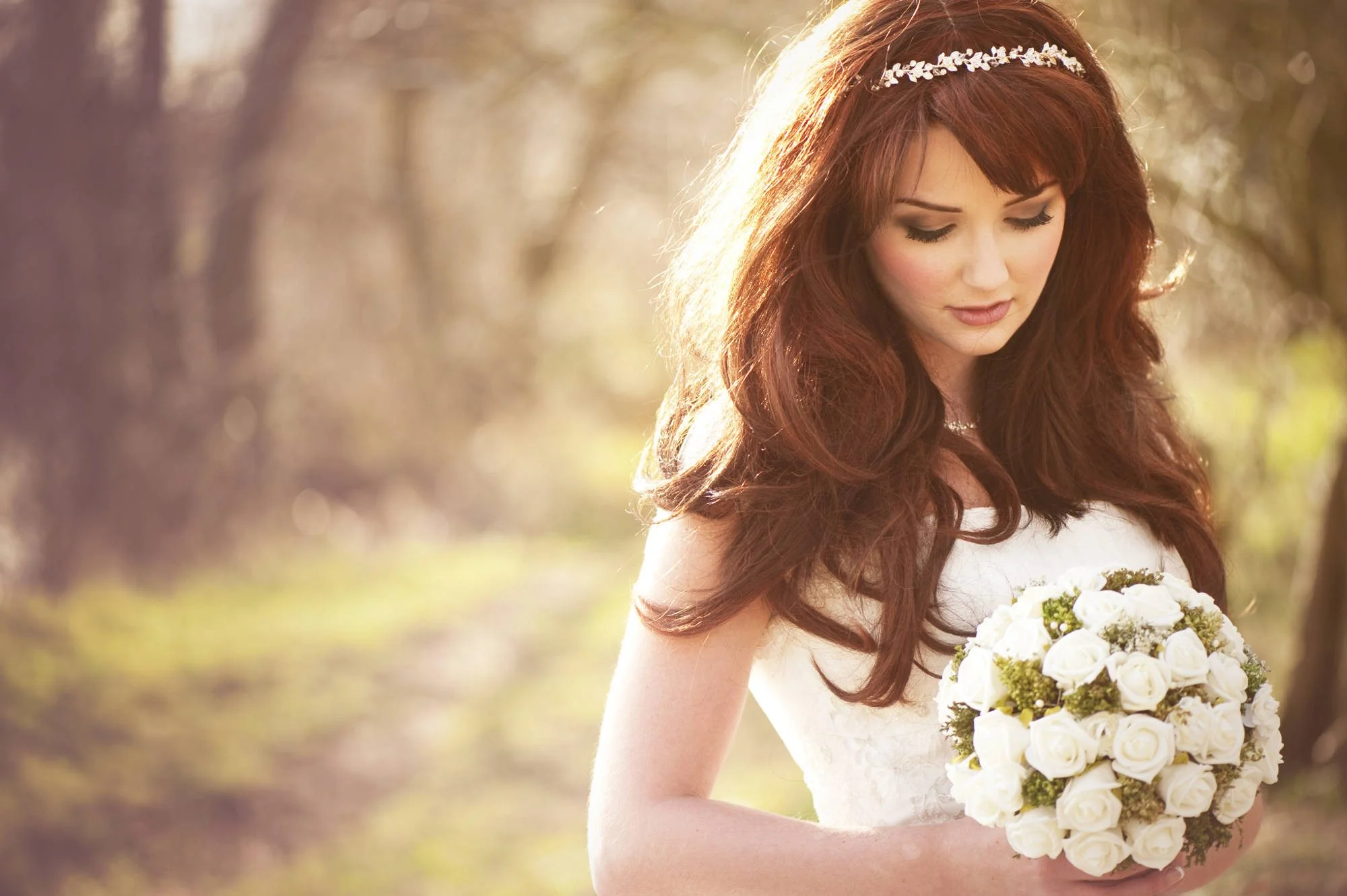 Sposa con bouquet in un prato al tramonto