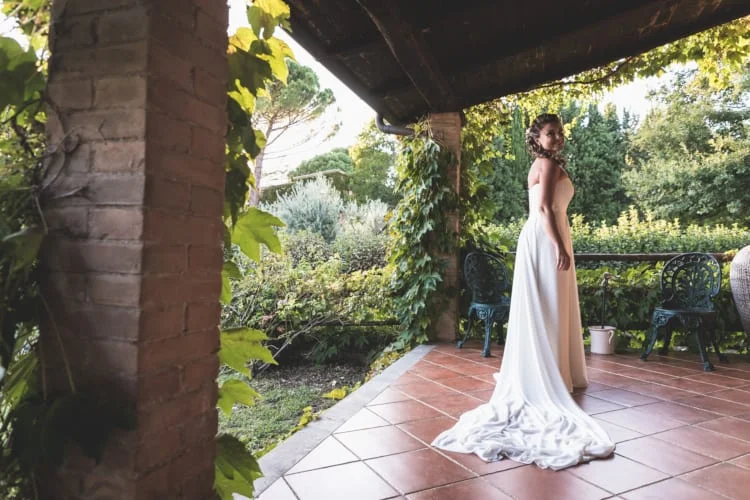 Sposa sotto il portico che guarda il giardino – Matrimonio a Tenuta di Polline