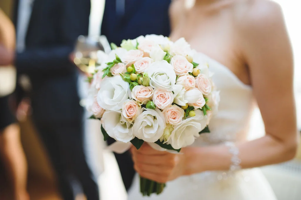Bouquet di rose bianche e rosa tra le mani della sposa